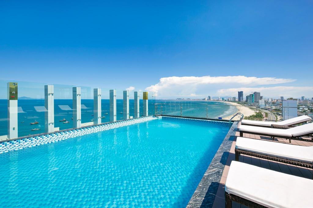 Outdoor swimming pool at Alisia Beach Hotel, with the sea and mountains beyond the deck