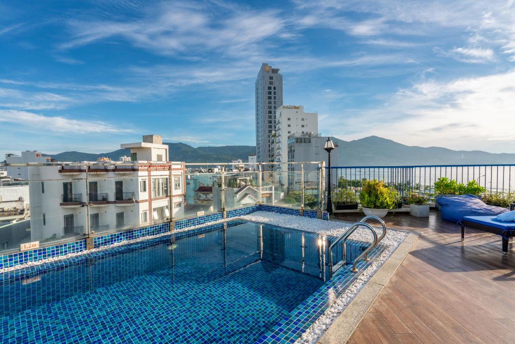 Rooftop pool at Cani Beach House at dusk, looking toward the city skyline