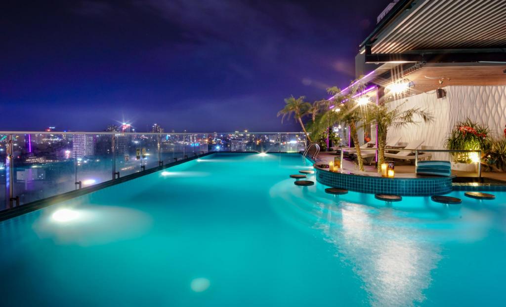 Outdoor swimming pool at Cicilia Danang Hotels & Spa, with loungers, palms and the hotel tower behind