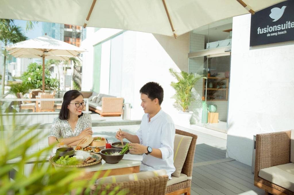White hotel tower with balconies and palms, the exterior photo on the Agoda listing for Fusion Suites Da Nang