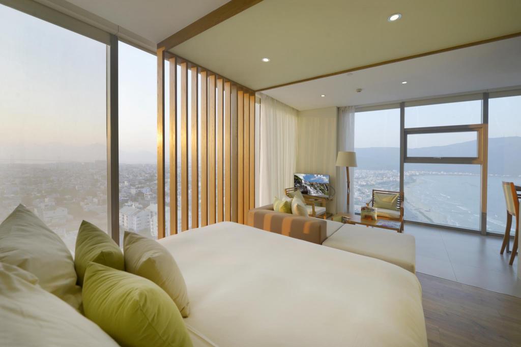 Guest room at Fusion Suites Da Nang with a Fusion Suites headboard, white bedding and a balcony