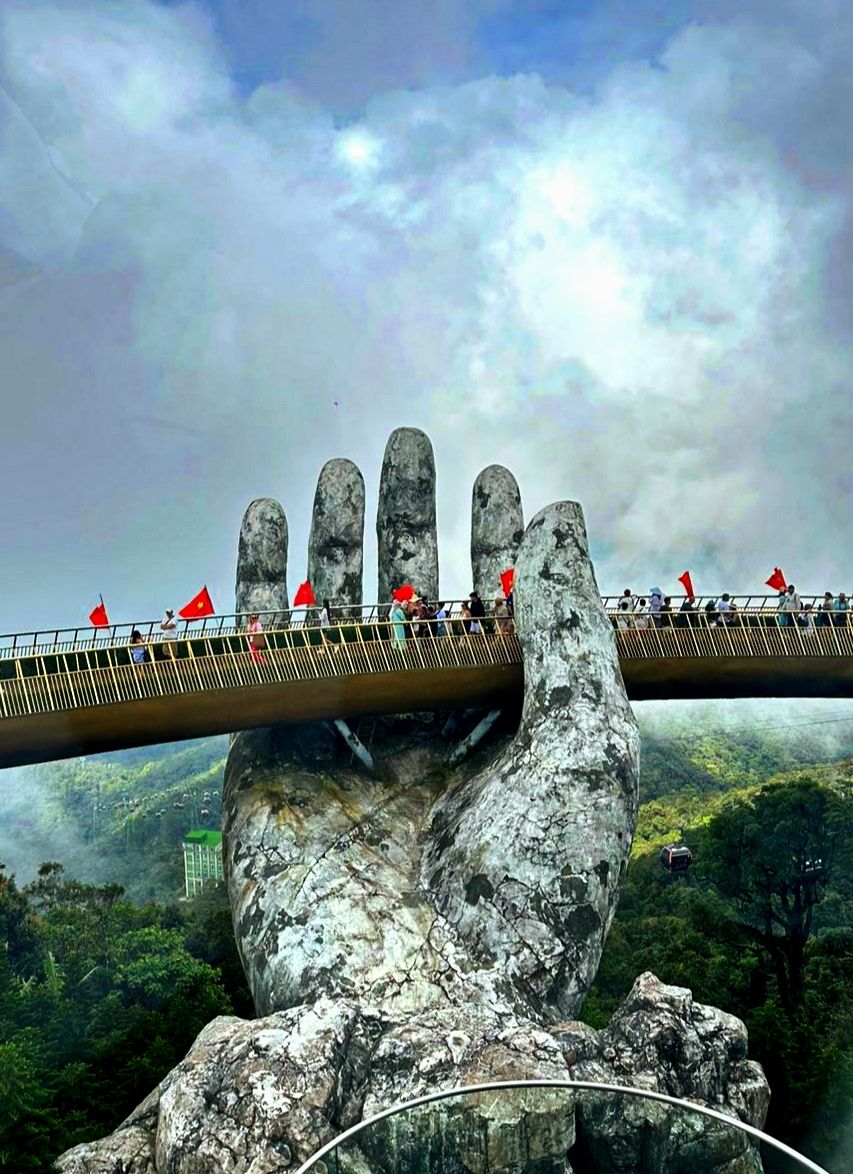 The Golden Bridge at Ba Na Hills, held aloft by two giant stone hands with forested mountains and mist below